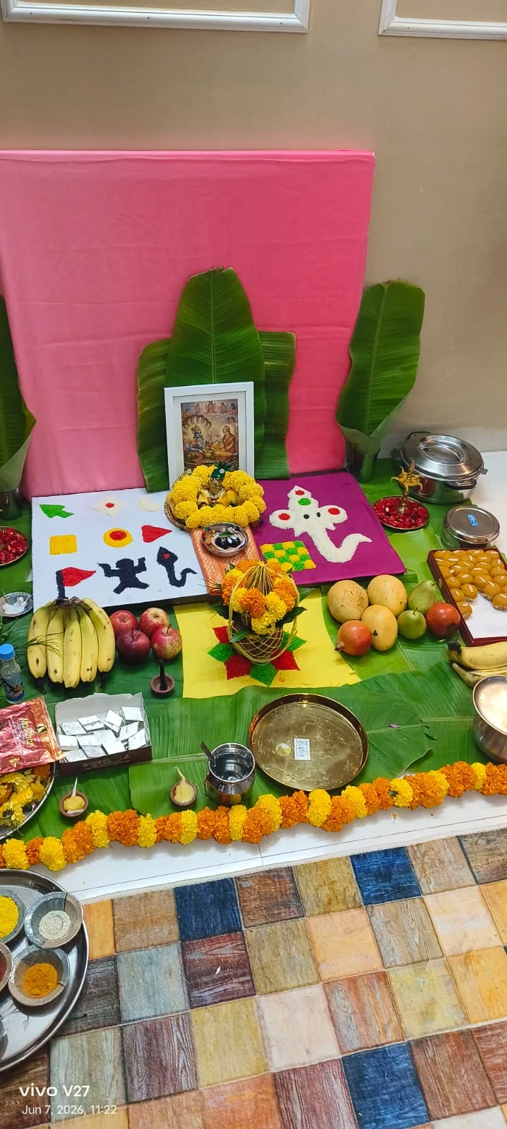 Vertical home puja altar with fruits, sweets, banana leaves and devotional picture