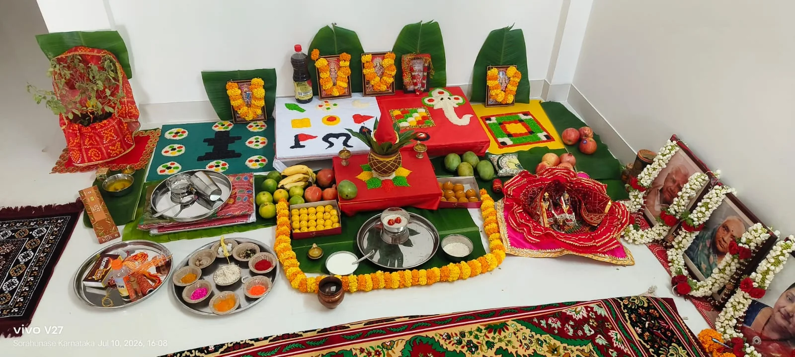 Complete home puja arrangement with banana leaves, deity frames, sweets, fruits and offerings